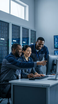 Team of engineers collaborating at a monitor in a data center server room