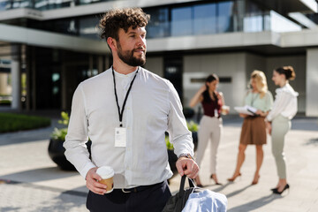 Young professional man with coffee outside modern office building