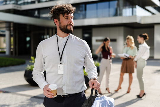 Young professional man with coffee outside modern office building