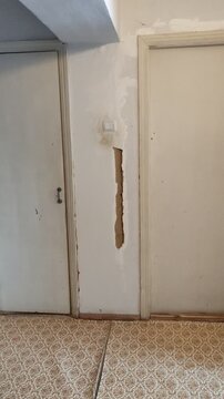 Damaged interior doors and cracked wall with peeling paint in old apartment