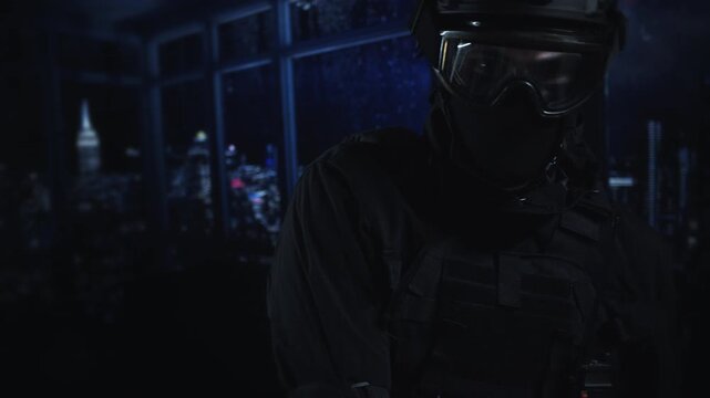 A soldier in full tactical gear and helmet stands in a dark room with a glowing blue city skyline behind him at night.