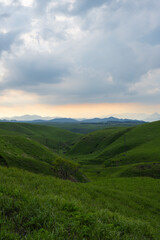 Fototapeta premium Sunset View of Orange Sky and Rolling Hills Along Aso Milk Road, Kumamoto, Japan