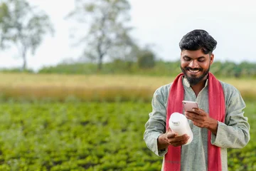 Young indian farmer using smartphone and checking product detail © PRASANNAPIX