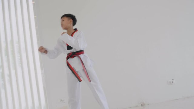 Young boy practices tying karate belt before martial arts training session in a bright room during the daytime