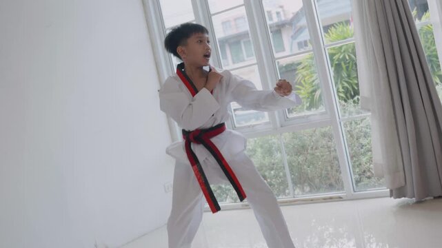 Young boy practices tying karate belt before martial arts training session in a bright room during the daytime