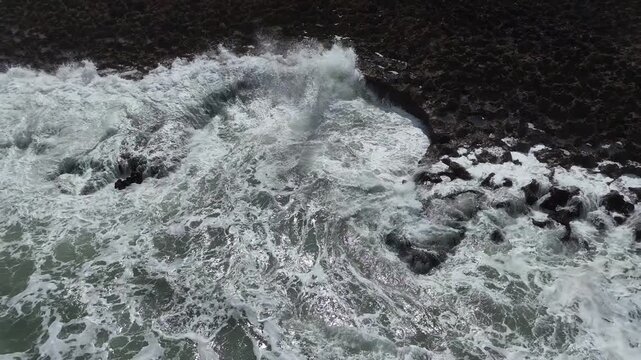 Aerial drone tracking shot pulls back to reveal the dramatic, rugged coastline of the Fisherman's Trail along the Rota Vicentina in Portugal, with powerful ocean waves crashing against rocks.
