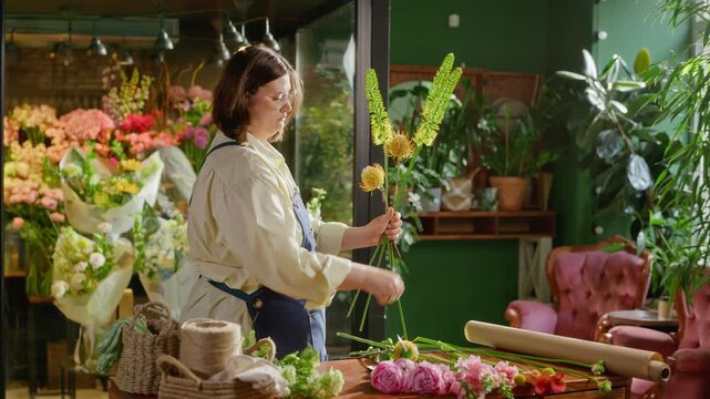 Young adult Caucasian woman florist arranging yellow flowers in flower shop. Footage is perfect for small business marketing, floristry workshops, and entrepreneurship campaigns