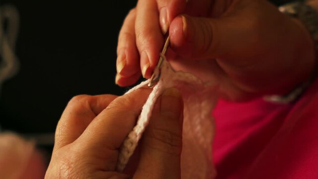 Woman's hands crocheting white yarn in extreme closeup.