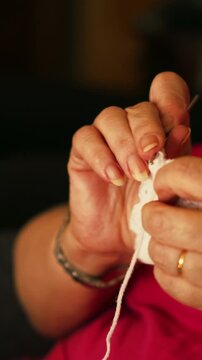 Mature woman's hands crocheting white yarn in extreme closeup.