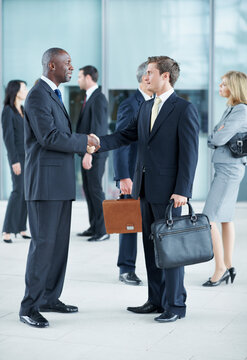 Business, men and handshake greeting in lobby for networking, introduction and seminar break. Global conference, people or shaking hands at event for headhunting, professional connection or workshop