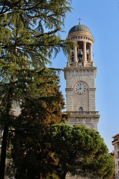 San Vittore Basilica bell tower framed by green trees in Verbania Intra Italy