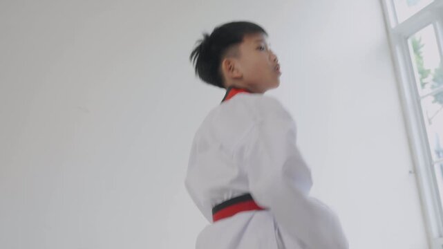 Young boy practices martial arts moves in a training studio near noon in warm weather