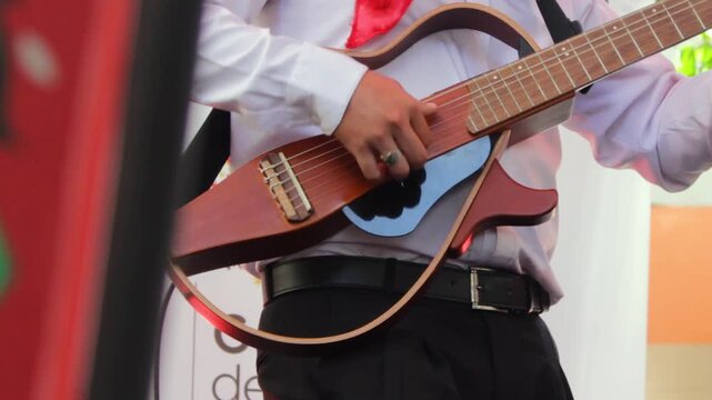 An unrecognizable man in traditional clothing plays a transparent guitar during a live show at the San Juan and San Pedro Festival in Neiva, Huila, Colombia. Concept of Colombian music and folklore