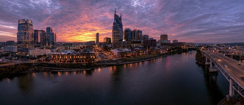 Vibrant sunset illuminates a city skyline reflecting in a wide river