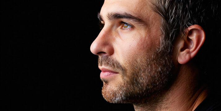Intense Side Profile of a Man with Short Hair and Beard Against a Dark Background