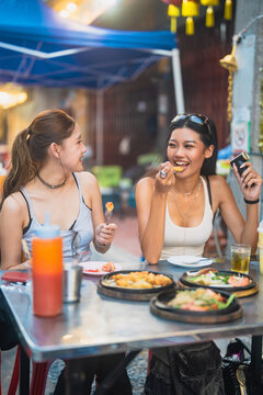 Authentic diversity Gen Z women shared experience enjoy eating streetfood local travel documentary style photography