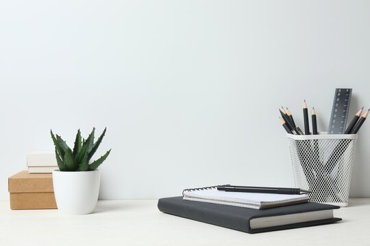 Front view of a minimalist home workspace with office supplies. White desk against a white wall