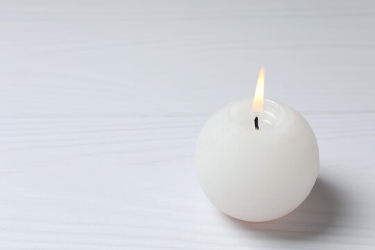 White candle in on wooden table, copy space