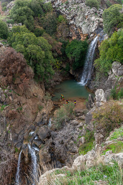 The Saar Falls in the Winter with people reppalling in the Golan Heights in northern Israel.
