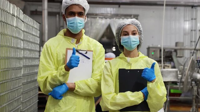 Two production supervisors overseeing the mackerel canning line give thumbs up displaying modern standardized documentation documenting every step of the production process.