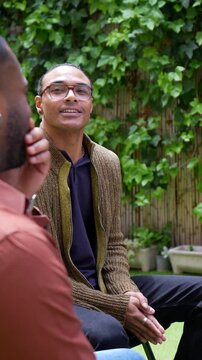 Diverse group of men participating in an outdoor therapy session, listening and offering support to each other, fostering a sense of community, connection, and emotional well being in a garden