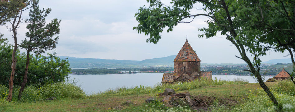 Sevanavank monastery panorama framed by green trees with copy space lake Sevan