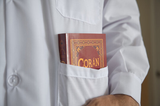 Person carrying the coran in a white lab coat pocket, symbolizing faith and profession