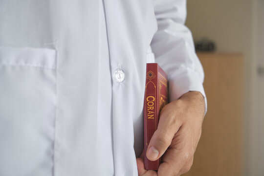 Muslim person carrying a copy of the holy book coran