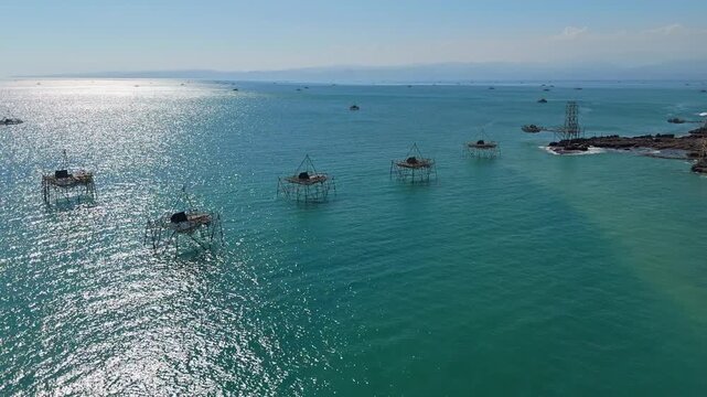 Aerial view of traditional Indonesian floating fish traps known as Bagang on a sparkling turquoise sea surface