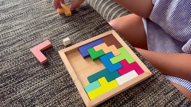 Child solving a wooden pentomino puzzle on a couch