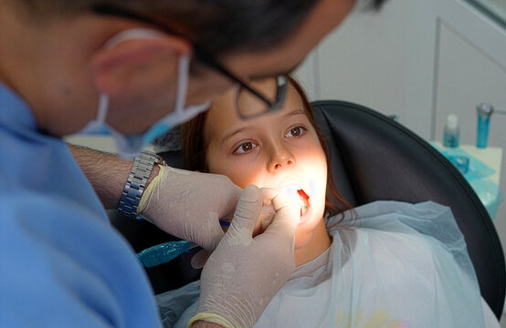 Dentist giving local anesthesia injection to little girl with dental carpule syringe close up.