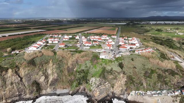 Aerial drone shot panning right over a coastal village Azenha do Mar, Portugal. Situated on cliffs overlooking the Atlantic, this remote settlement is part of the Rota Vicentina Fisherman's Trail.