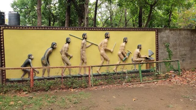 Satirical Wall Relief Art Showing Human Evolution Ending At Computer Desk