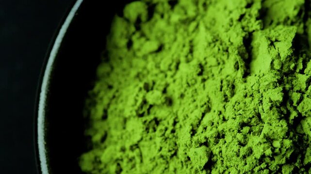Matcha green tea powder rotating in a smooth circular motion with an extreme close-up view, revealing the rich texture of premium Japanese matcha.