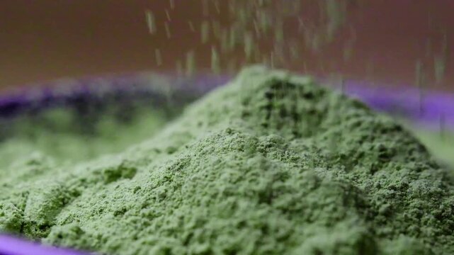 Matcha powder falling in an extreme macro close-up, revealing the soft texture and vibrant green color of premium organic green tea. Ideal for healthy beverage advertising, Japanese tea culture.