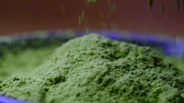 Premium organic matcha powder pouring into a bowl in a detailed macro shot, capturing the fine texture and natural movement of authentic Japanese green tea.