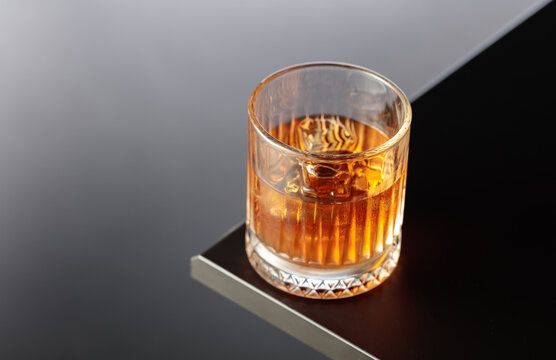 Whiskey with ice on a black table.