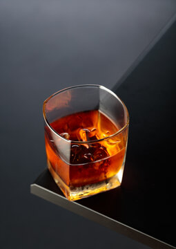 Whiskey with ice on a black table.