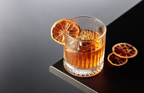 Old-fashioned cocktail with ice and a dried orange slice.