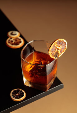 Old-fashioned cocktail with ice and a dried orange slice.