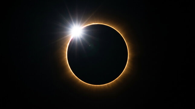 Solar eclipse diamond ring effect with bright flash and glowing corona ring.