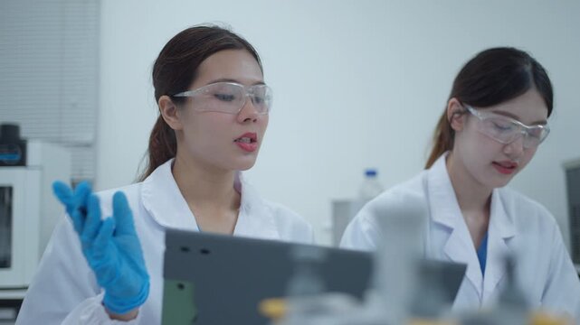 Two female scientists collaborating and discussing research results on a tablet computer in a modern laboratory