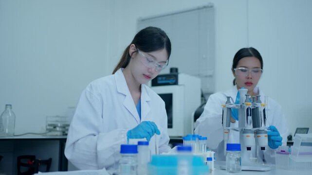 Two female scientists conducting research and working with test tubes and pipettes in a modern medical laboratory
