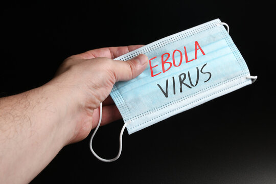 A man's hand holds out a protective mask with "Ebola virus" written on it. Concept for Ebola virus disease.