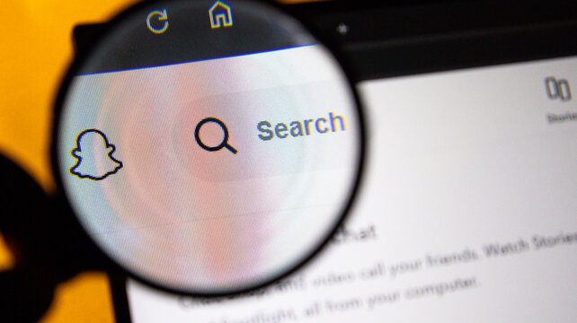 Magnifying glass over Snapchat ghost icon and search bar on a digital screen with pixel detail