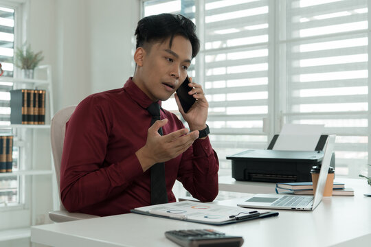 Focused Businessman Talking on Smartphone at Office Desk