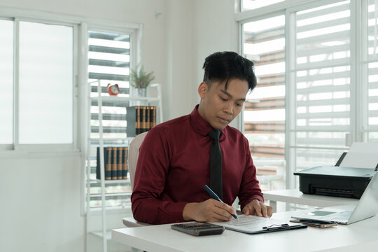 Focused Asian Businessman Calculating Finances at Office Desk