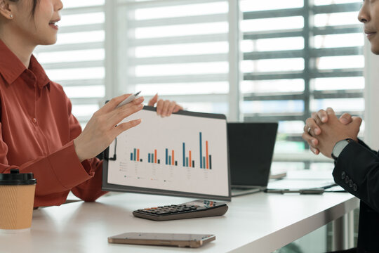 Businesswoman Presenting Bar Chart to Colleague at Office Desk