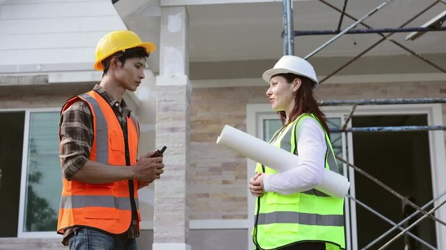 Civil engineer and architect discussing a blueprint on a construction site while checking building progress