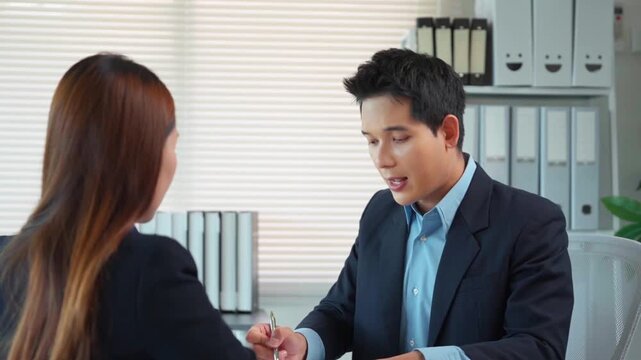 Asian businessman interviewing a job candidate in a modern corporate office and explaining the employment contract terms